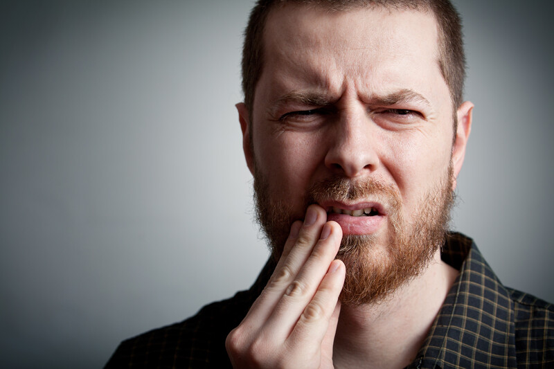 Man holding his face in pain before root canal therapy at Highland Family Dental in Casper, WY